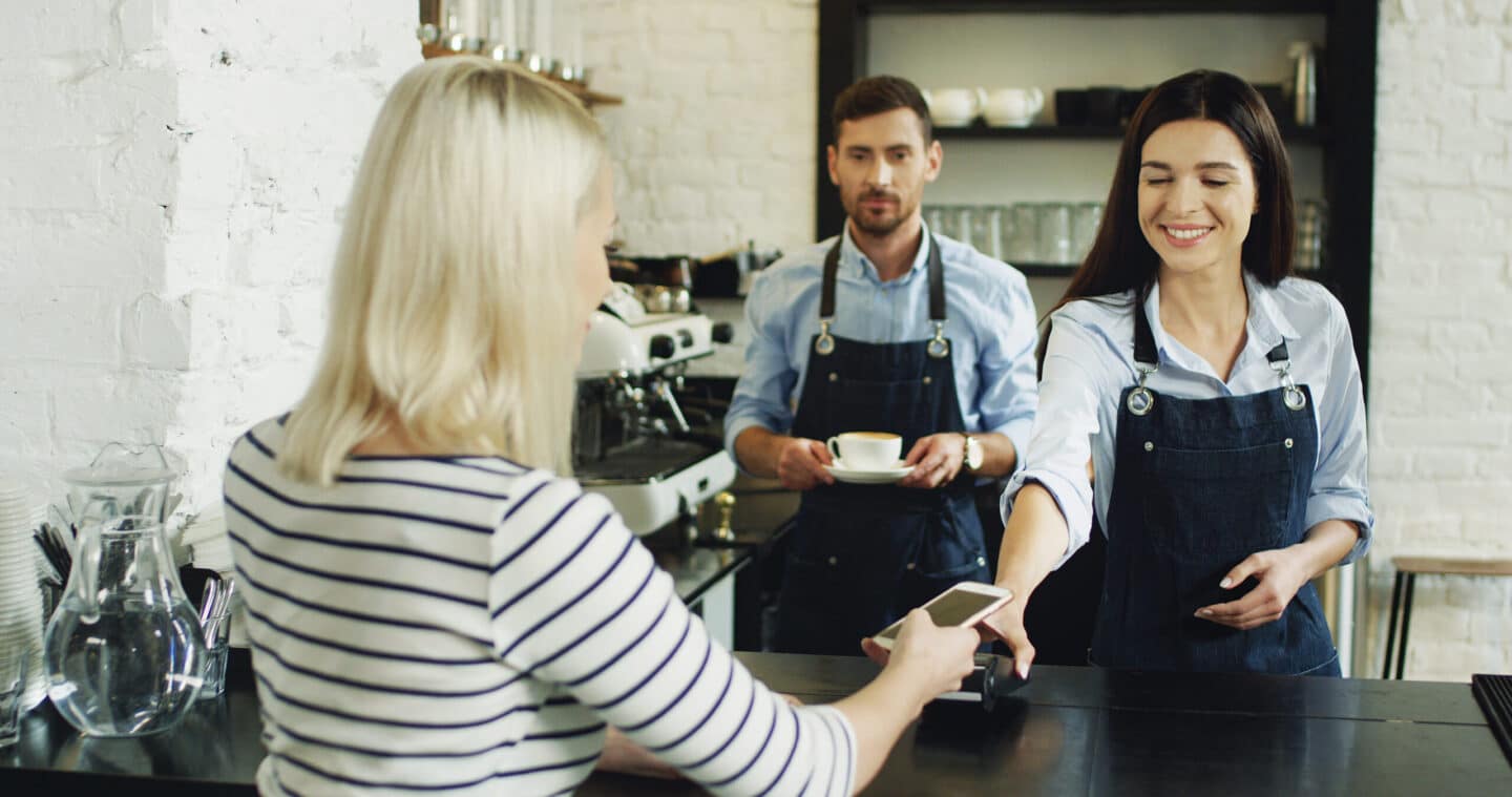 Customer uses phone at coffee shop to pay on an upgraded POS system